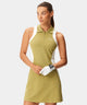 Woman on a golf course wearing the Cora TX Dress in sheen green with white side panels, featuring a sleeveless design, zip-front ribbed collar, and a flattering athletic fit ideal for active play and warm weather.