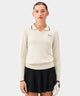 Woman wearing the white Ella Knit Top with long sleeves, black contrast tipping at the collar and cuffs, and a minimal Macade logo on the left chest, paired with a black golf skirt and a white golf glove.