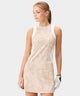 Woman wearing the Macade Golf Inez Sleeveless Dress in a beige botanical print with white side panels, featuring a fitted, above-the-knee silhouette and minimal branding, designed for modern golf style and versatile everyday wear.