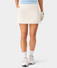 Front view of the TX Air Skirt in ivory, worn by a golfer, featuring a wide waistband, discreet front pockets, and a clean, modern silhouette designed for comfort and effortless movement.