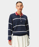 Woman wearing the Club women’s golf sweater in navy with white horizontal stripes, a red polo collar, and ribbed cuffs, styled with a white golf skirt for a modern, preppy look.
