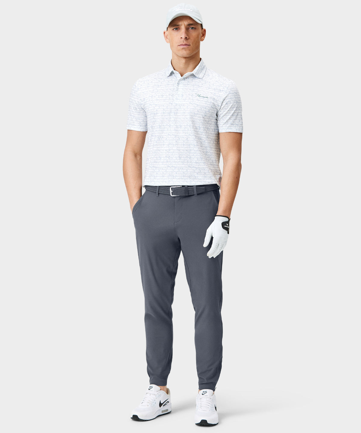 Male golfer wearing Macade Golf Four-Way Stretch Jogger in navy, styled with a performance polo, belt, and golf glove, showcasing the jogger’s tailored fit, cuffed ankles, and minimal, modern design for both on-course and everyday versatility.