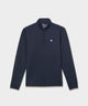 Man wearing a navy blue Macade Golf Therma Quarter Zip with a minimalist white chest logo, paired with beige golf pants and a navy cap, showcasing the sweater’s clean lines and athletic fit for a refined, modern golf look.