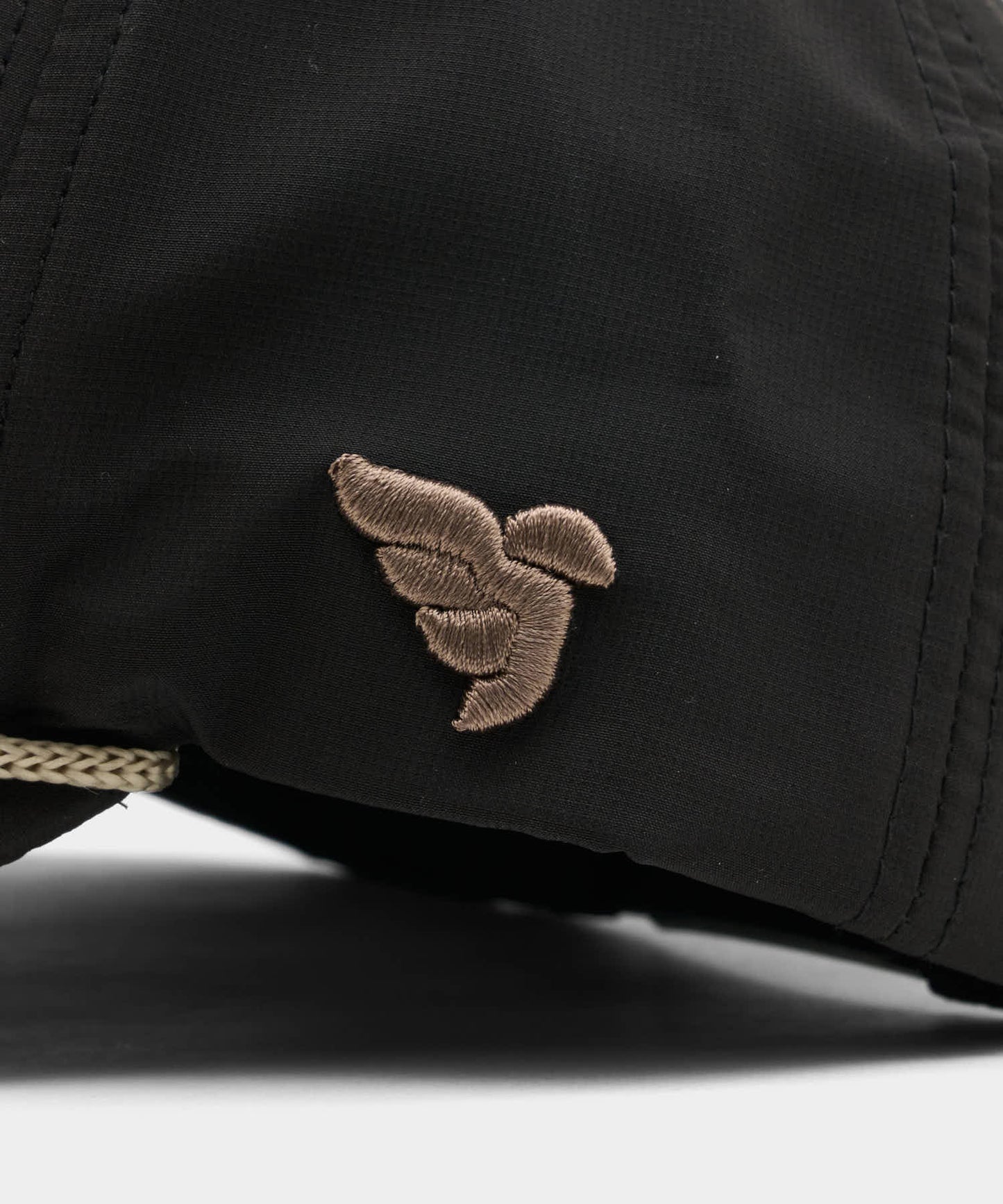 Close-up of the Macade Rope Course Snapback in black, highlighting the tonal brown embroidered logo on the side panel and the premium rope accent above the brim for a refined, minimalist finish.