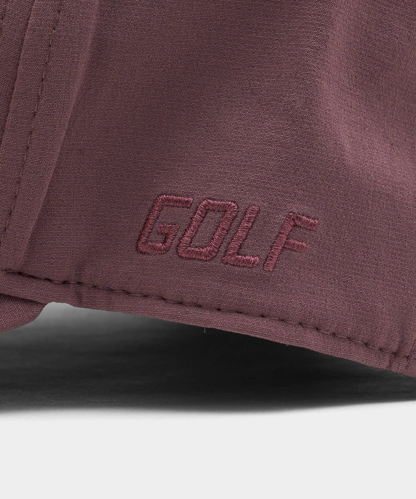 Detail view of the mauve Range Snapback by Macade Golf, showcasing the tonal GOLF embroidery and premium stitching on the soft, stretchable fabric.