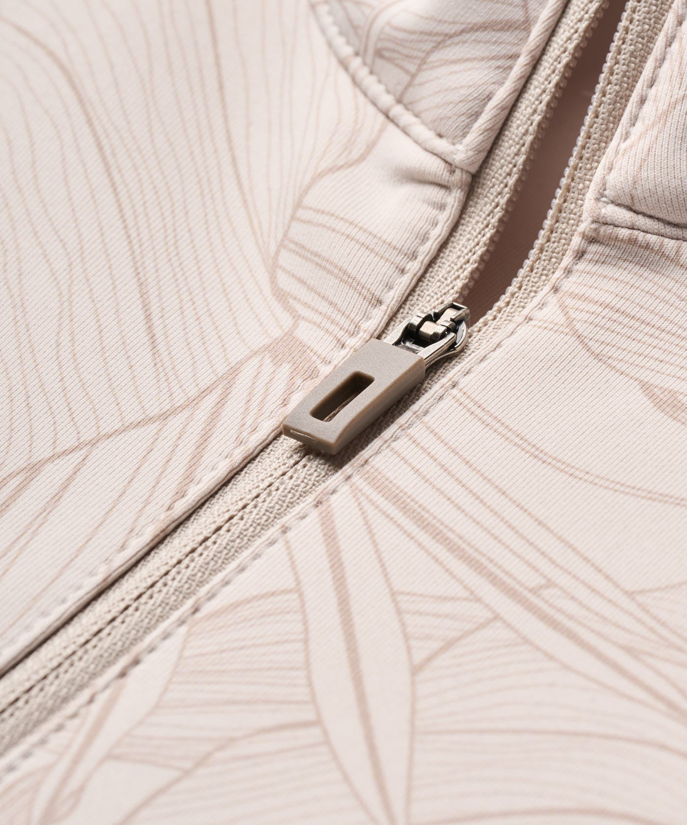Close-up of the Therma Quarter Zip by Macade Golf in palm beige, featuring a premium zipper and smooth, high-stretch fabric with subtle tonal pattern detailing for a refined, modern finish.