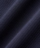 Woman wearing the Macade Cora TX Dress in dark blue, featuring a sleeveless, above-the-knee design with a ribbed collar, zip front, contoured side panels, and sleek minimal branding, styled for golf with a white glove.