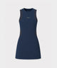 Woman wearing the Macade Golf Inez Sleeveless Dress in navy, featuring a fitted, above-the-knee silhouette and minimal branding, styled with a golf glove and standing outdoors by a railing.
