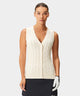 Sleeveless women’s golf sweater vest in ivory with a cable knit pattern, deep V-neck, and button front, styled with a black skirt and golf glove for a refined, modern look on or off the course.