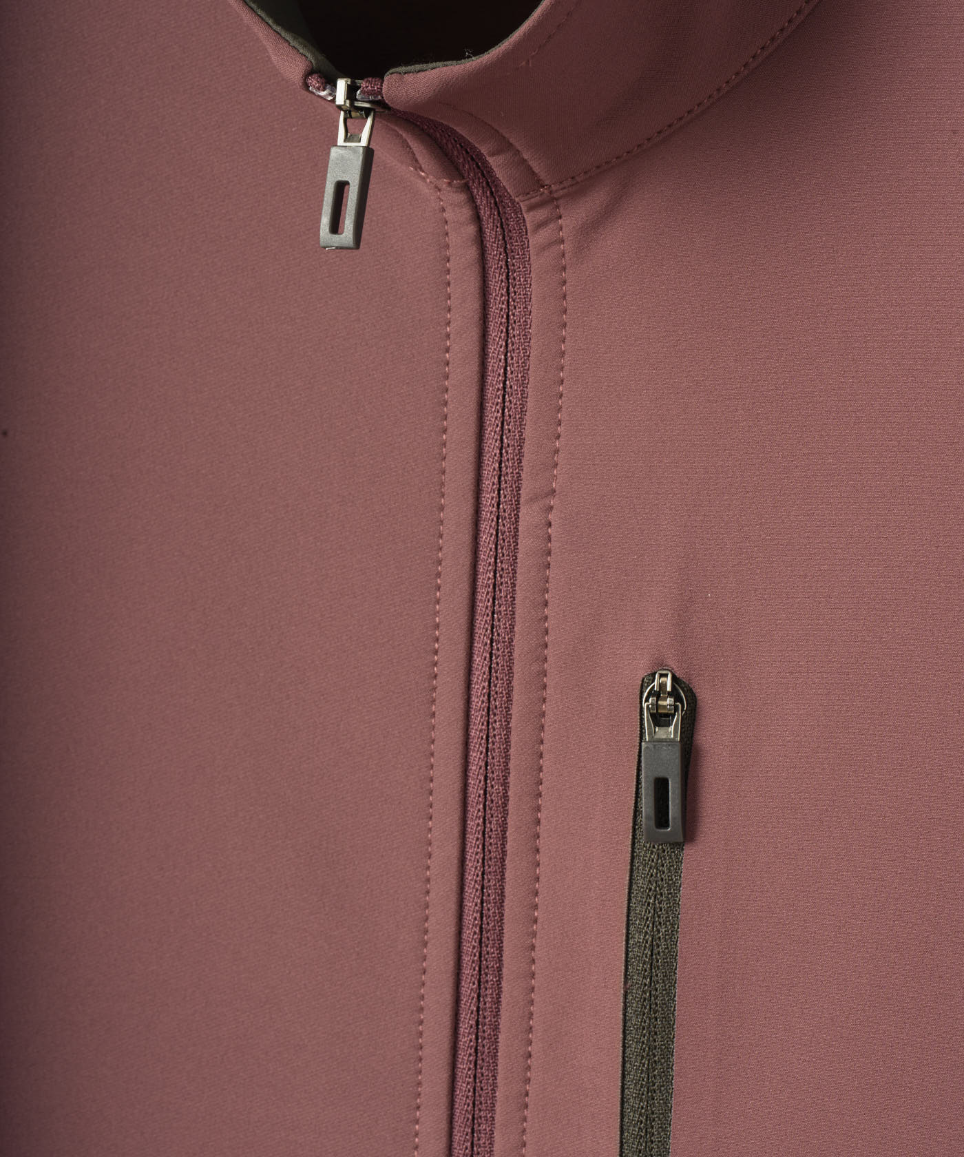 Close-up of the Macade Golf Storm Wind Jacket in mauve, showing the smooth soft shell fabric, high collar, and sleek zippered front and chest pocket with minimal detailing.