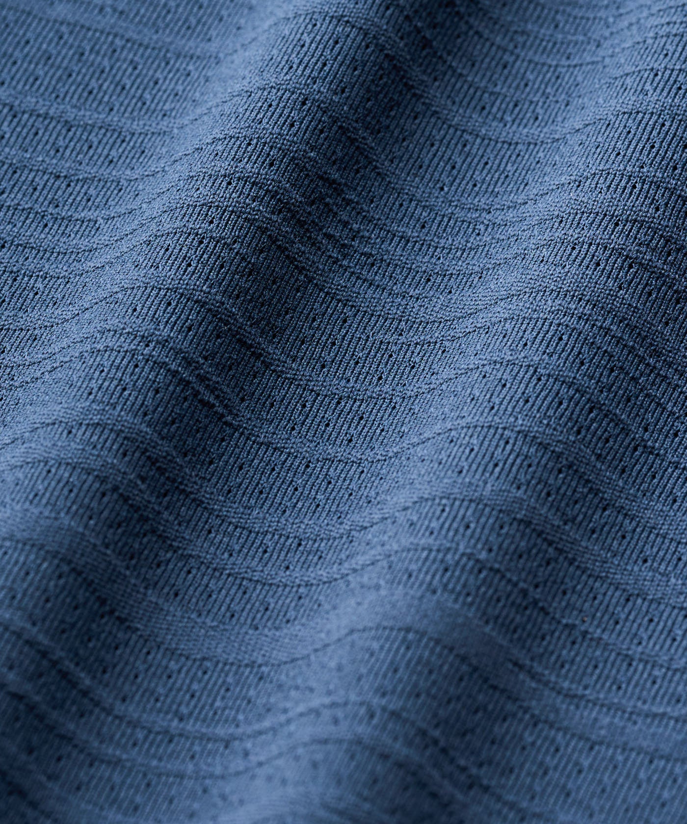 Close-up of the Paige Sleeveless Shirt fabric in steel blue, highlighting its premium textured knit with subtle horizontal lines and breathable, lightweight construction.