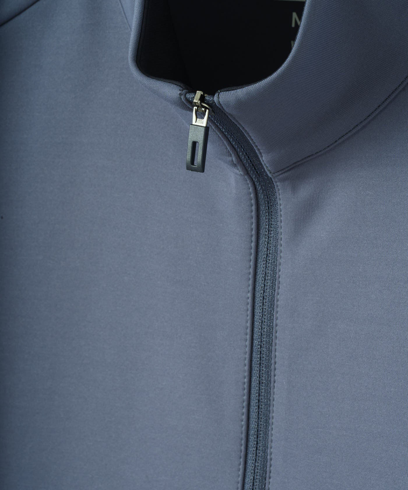 Close-up of the Stone Blue Macade Golf Therma Vest highlighting the smooth, premium polyester-spandex fabric and the clean, structured quarter-zip collar detail.